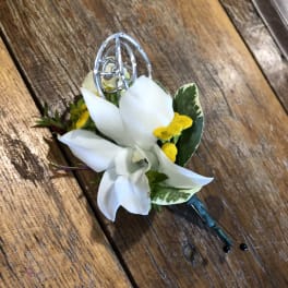 White orchid boutonniere with yellow accents and a silver pin