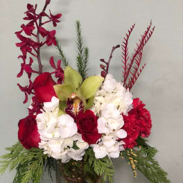 Red roses and white hydrangeas in a glass vase with green foliage