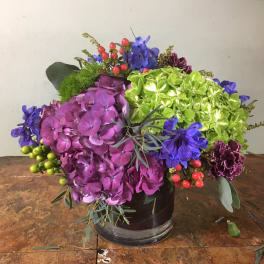 Colorful flower arrangement in a dark vase with purple and green blooms