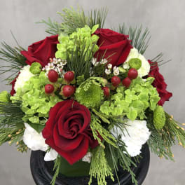 Red roses with green and white flowers in a black vase