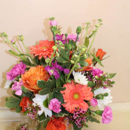 Mixed bouquet of orange, pink, and white flowers in a painted vase