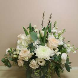 White floral arrangement in a dark vase with roses and chrysanthemums
