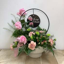 Pink roses and carnations in a white vase with a memorial sign