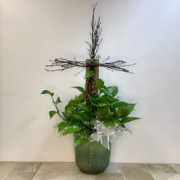 Potted plant arrangement with a wooden cross and white ribbon