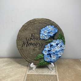 Round memorial plaque with blue flowers and the words "In Loving Memory"