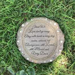 Round memorial plaque with engraved text lying in grass