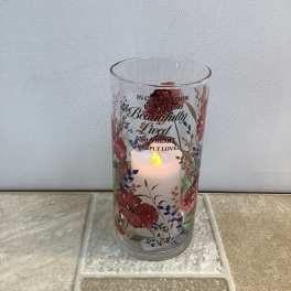 Lit memorial candle in a floral glass holder