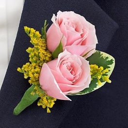Pink rose boutonniere with yellow filler flowers on dark fabric