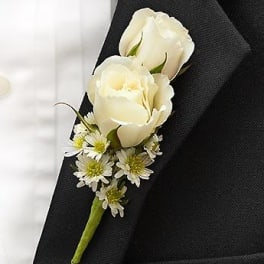 White rose boutonniere with small daisy accents on a black suit lapel