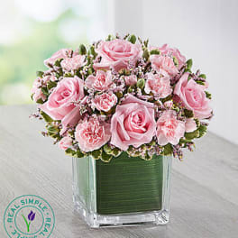 Pink roses and carnations in a clear square vase