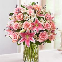Pink roses and lilies arranged in a clear glass vase