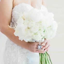 Bride holding a white wedding bouquet with a photo charm