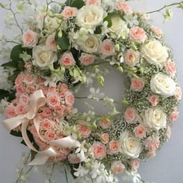 Heart-shaped floral wreath with pink and white roses and ribbon