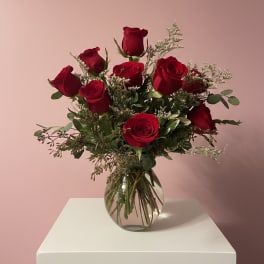 Arrangement of red roses with white filler flowers in a round clear glass vase