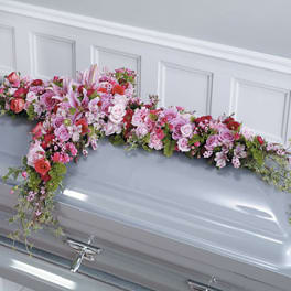 Pink and white floral spray arranged on a silver casket