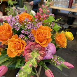 Bouquet of orange roses, pink tulips, and purple filler flowers