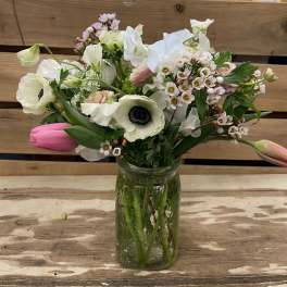 Mixed white and pink flowers arranged in a glass jar vase