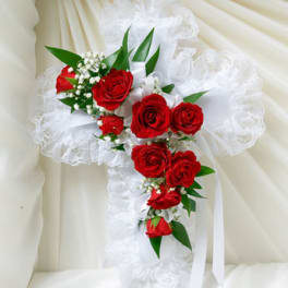 Red roses arranged on a white lace cross with ribbon