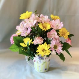 Pink and yellow flowers arranged in a floral mug