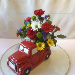Flowers arranged in a red ceramic truck planter
