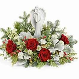 Red roses and white flowers arranged around an angel figurine