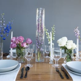 Table centerpiece with roses, delphinium, and tall glass cylinders