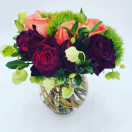 Bouquet of dark purple and peach roses in a glass vase