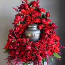Red rose funeral arrangement around a gray urn