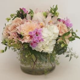 Pastel bouquet of roses, hydrangeas, orchids, and dahlias in a glass vase