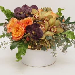 Orange roses and orchids arranged in a gold container