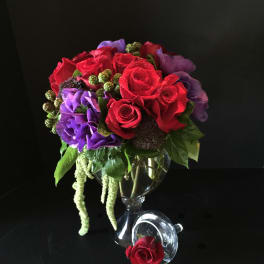 Red and purple rose bouquet in a clear glass vase