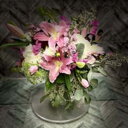 Pink lilies and white blooms arranged in a round bouquet