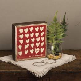 Heart-patterned decorative block beside a small jar of faux greenery