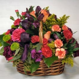 Basket arrangement of roses, carnations, and purple flowers