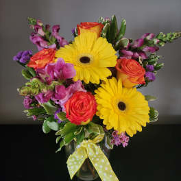 Bouquet of yellow gerbera daisies and orange roses in a glass vase