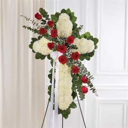 Standing floral cross with red roses and white blooms on an easel