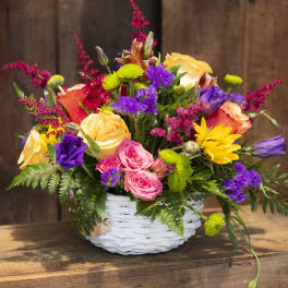 Colorful mixed flower arrangement in a white wicker basket