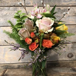 Mixed bouquet of roses, lilies, and pussy willow in a glass vase