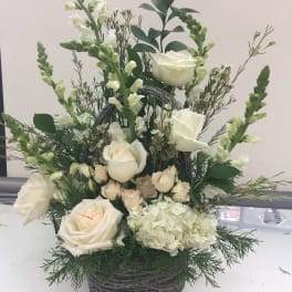 White roses and snapdragons arranged in a wicker basket