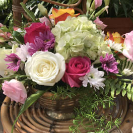 Mixed bouquet of roses, hydrangea, and daisies in a copper vase