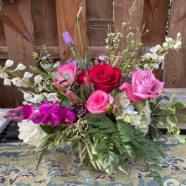 Mixed bouquet of roses, orchids, and white blossoms in a glass vase