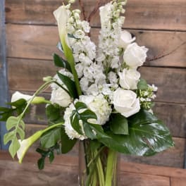 White roses and calla lilies in a clear glass vase