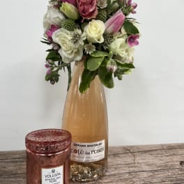 Pink and white rose bouquet in a glass bottle with a rose candle in front
