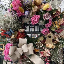 Large floral wreath with pink blooms, butterflies, and a burlap bow