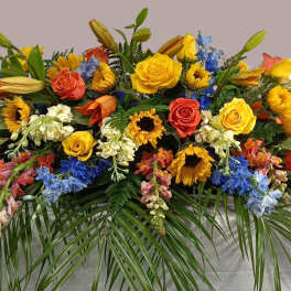 Large casket spray with yellow, orange, blue, and white flowers