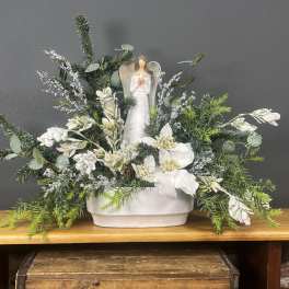 Winter floral arrangement with a small angel figurine in a white container