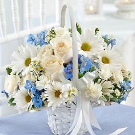White basket of daisies, roses, and blue flowers with a ribbon
