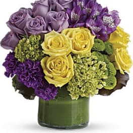 Purple and yellow roses in a green glass vase