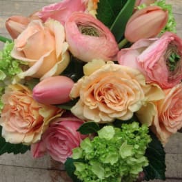 Bouquet of peach and pink roses with green hydrangea clusters
