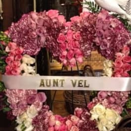 Pink and purple floral funeral wreath with a white ribbon reading AUNT VEL